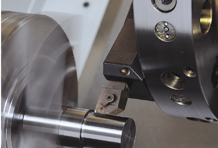 A cylindrical metal part being cut in a CNC lathe